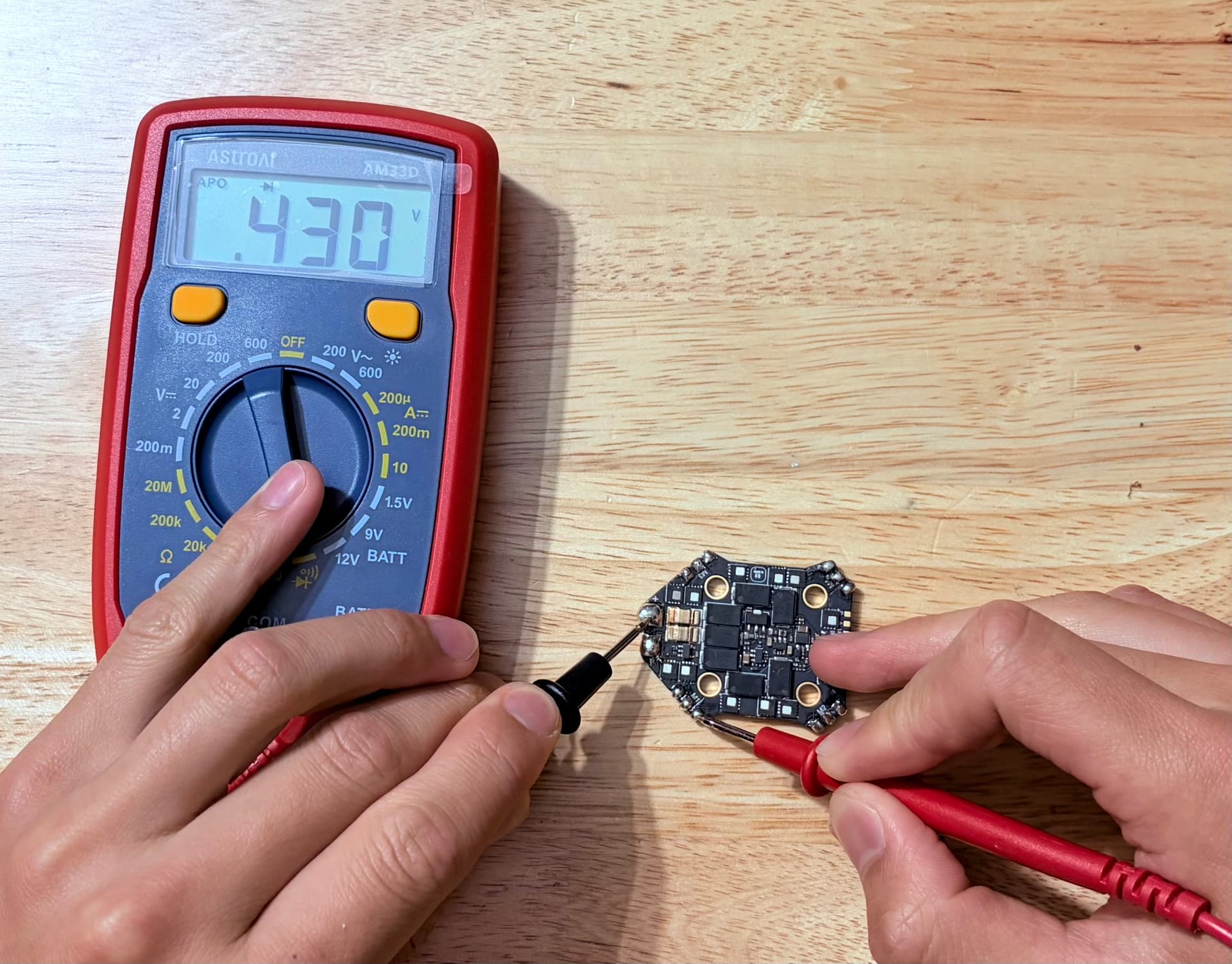 Multimeter reading 0.430 V while black probe is on the ESC positive pad and red probe is on a motor phase pad.